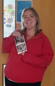 Pregnant woman holding baby scan photos