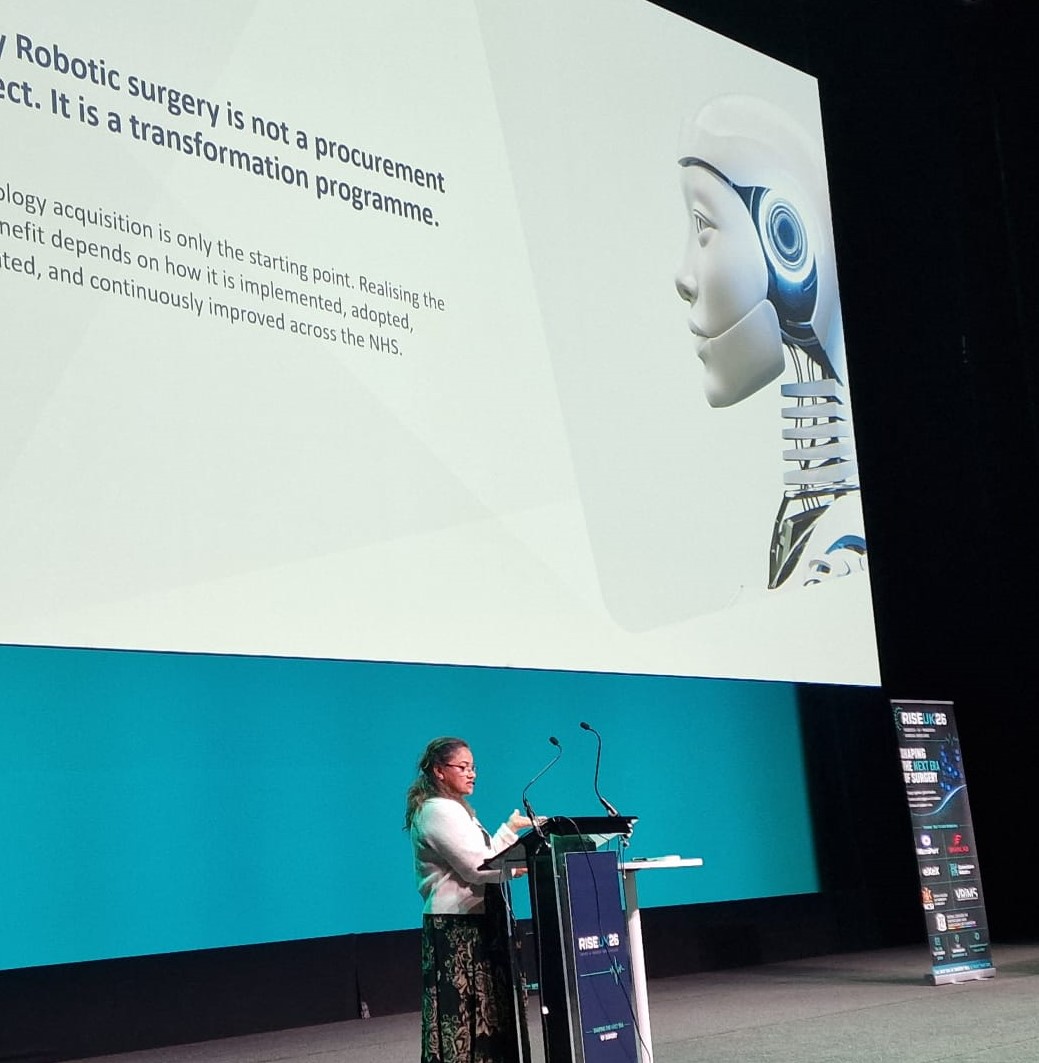 Mamta Bajre presenting at RISE UK 2026. Her slide reads "robotic surgery is not a procurement project. It is a transformation programme."
